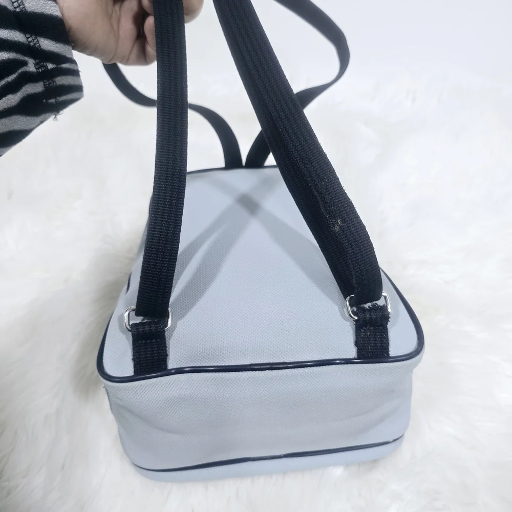 Lacoste mini backpack in a soft light blue shade with navy blue trim accents.
